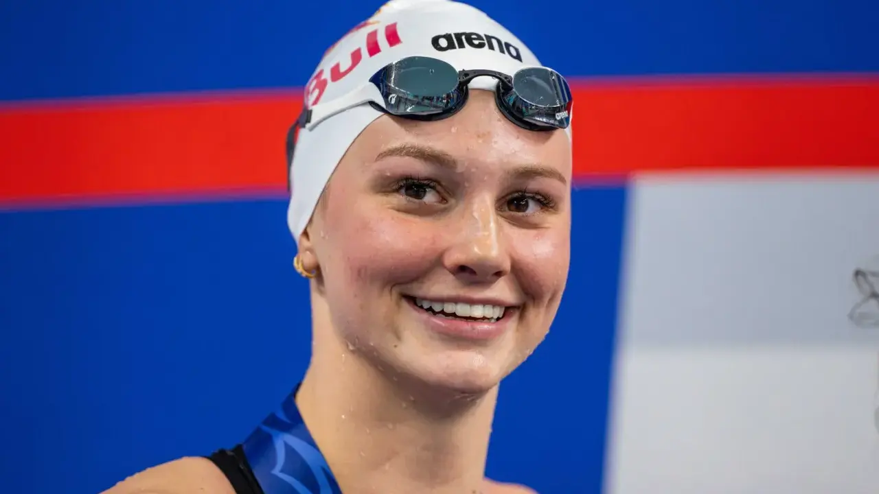 Sorriso raggiante di Summer McIntosh, nuotatrice con cuffia e occhialini, pronta per una gara.