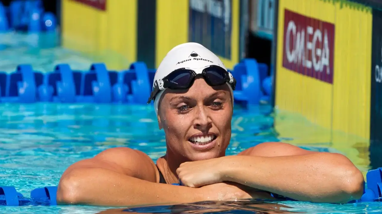 Amanda Beard, nuotatrice sorridente in piscina, con cuffia e occhialini, pronta per la gara.