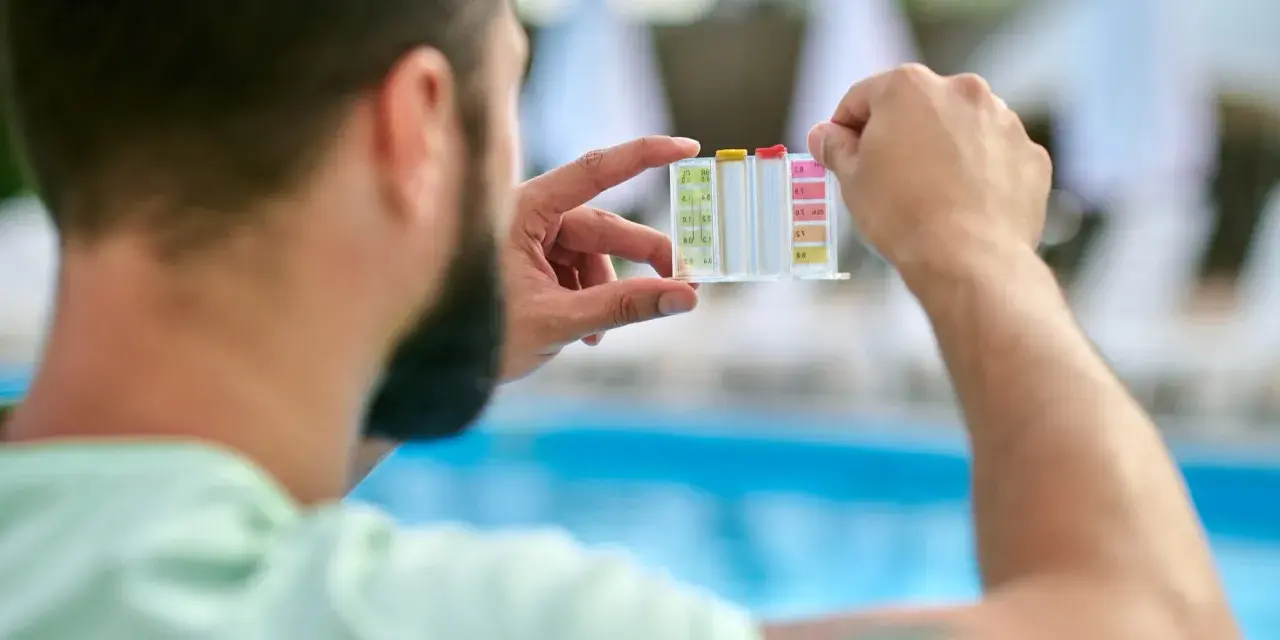 Uomo controlla il kit per acidificare l'acqua della piscina, analizzando i livelli di pH e cloro.