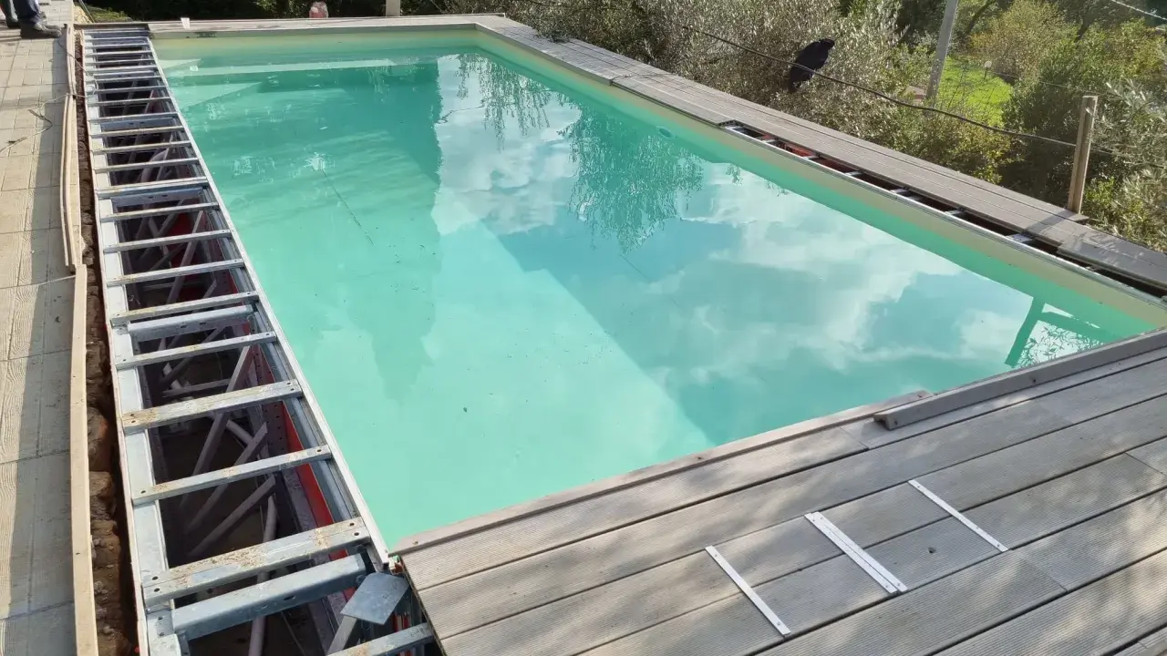 Struttura metallica a vista per piscina fuori terra, con pannelli in legno in fase di posa. Si nota un leggero cedimento della struttura.