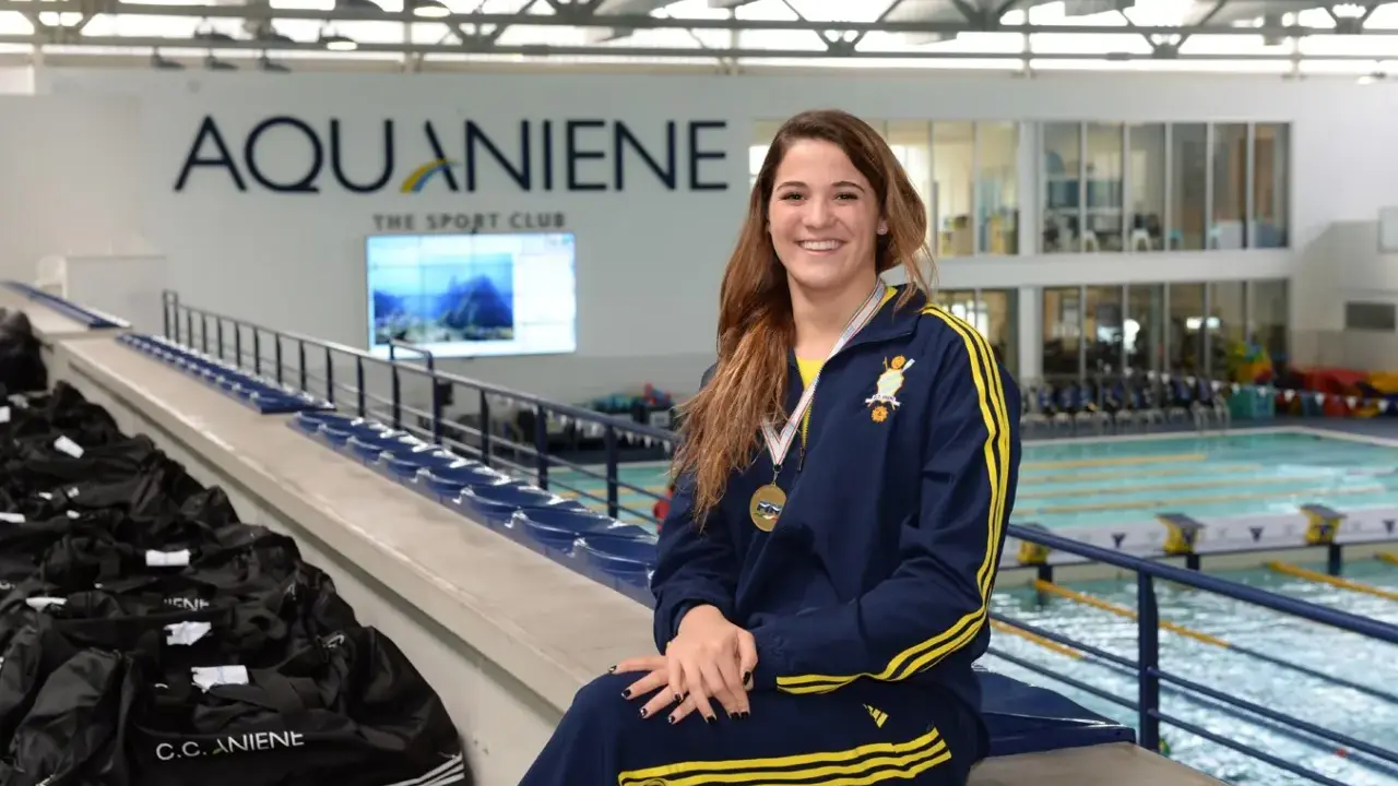Rachele Ceracchi, nuotatrice sorridente con medaglia al collo, posa in un centro sportivo con piscina.