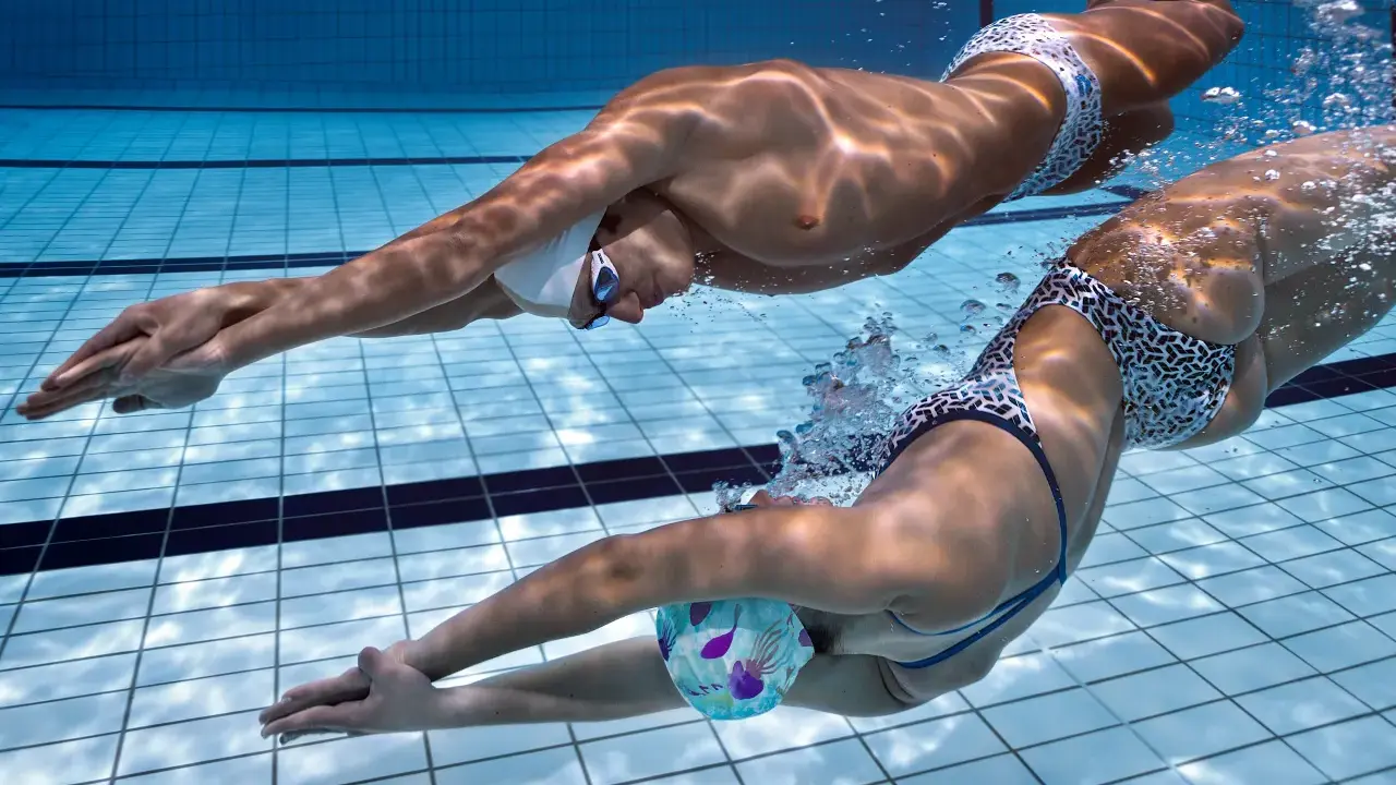 Due nuotatori si allenano in piscina, un uomo e una donna, in un intenso allenamento ipossico.