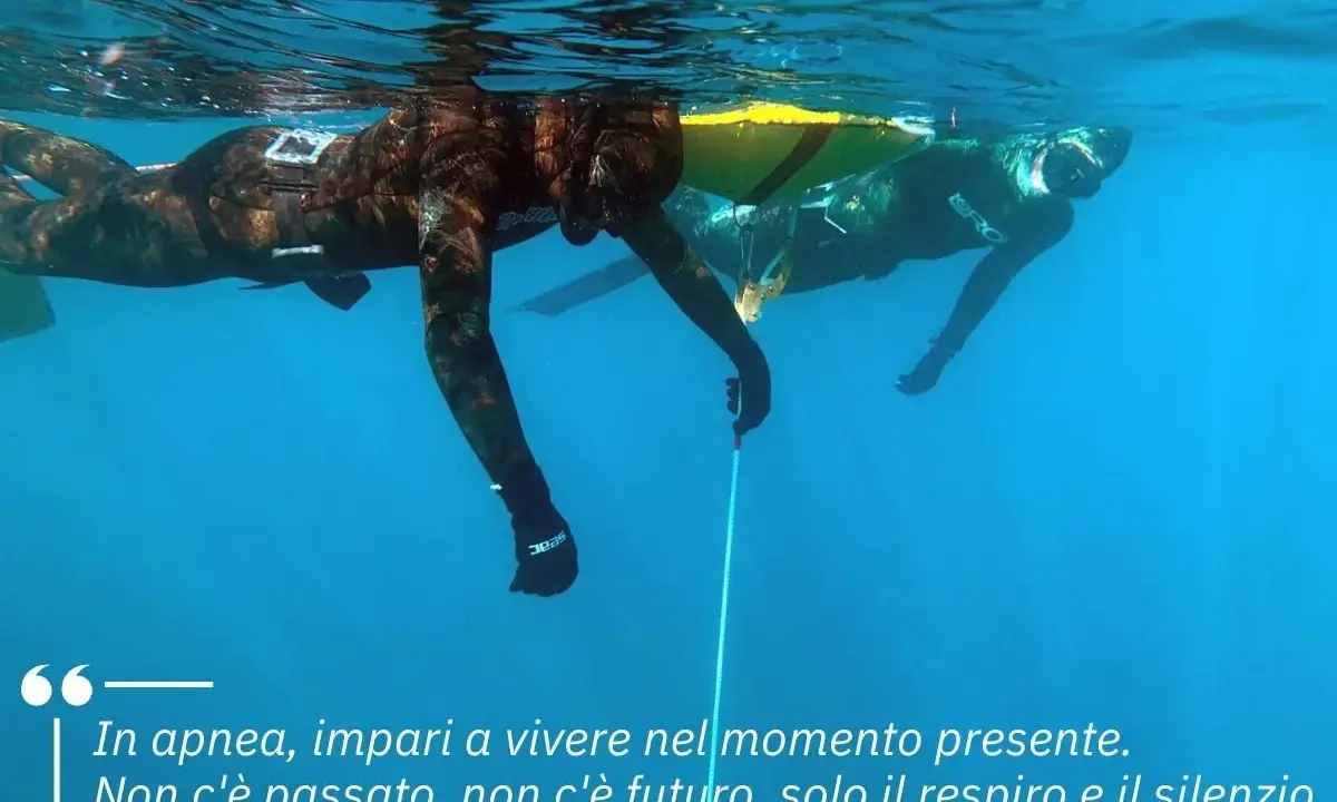 Due apneisti nuotano sott'acqua, uno vicino alla superficie. Imparare a trattenere il respiro, come rompere il fiato, porta a vivere il momento presente.