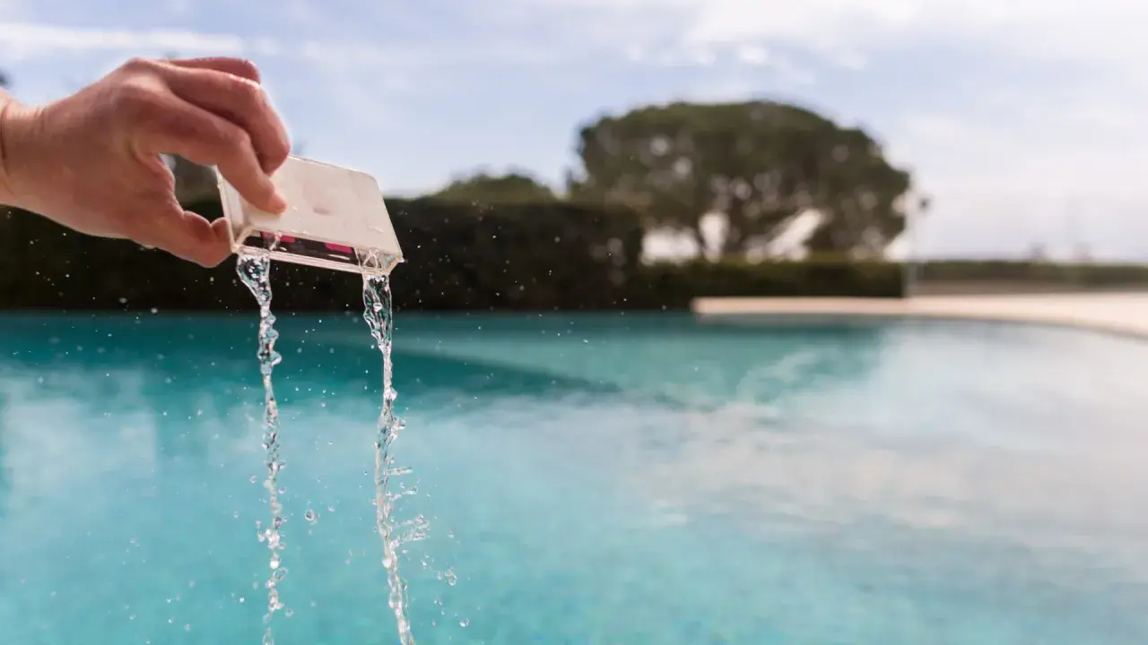 Mano che versa acqua da un contenitore per testare il cloro della piscina.