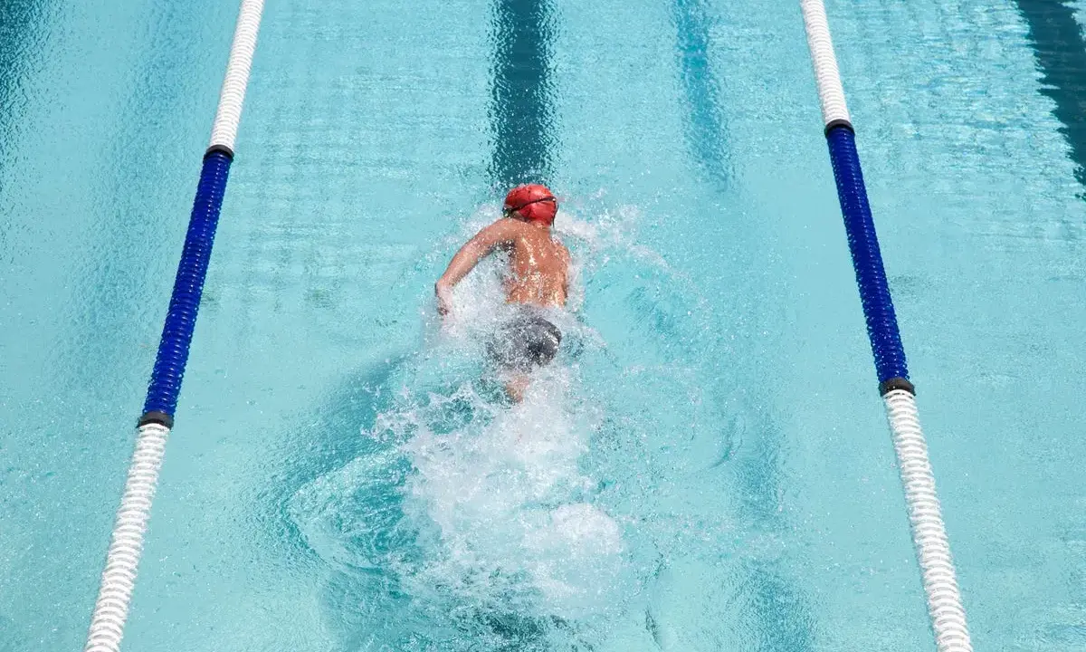 Nuotatore in corsia, godendosi i benefici del nuoto libero. L'acqua cristallina e il movimento fluido del corpo evidenziano la libertà e il benessere.