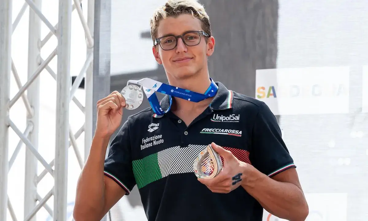 Davide Grossi, nuotatore italiano, mostra con orgoglio le sue medaglie d'argento e di bronzo, frutto di un'ottima prestazione.