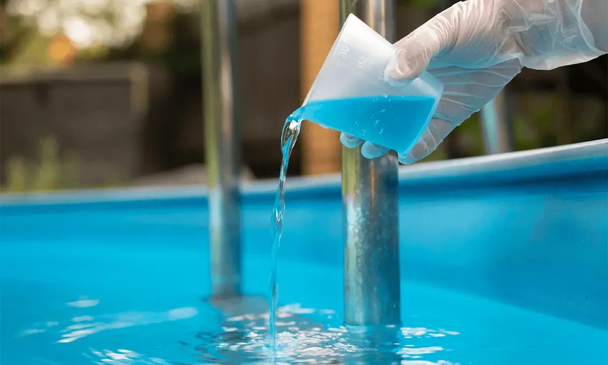 Versando antialghe piscina. Dopo quanto fare il bagno? La soluzione azzurra cade in acqua limpida.