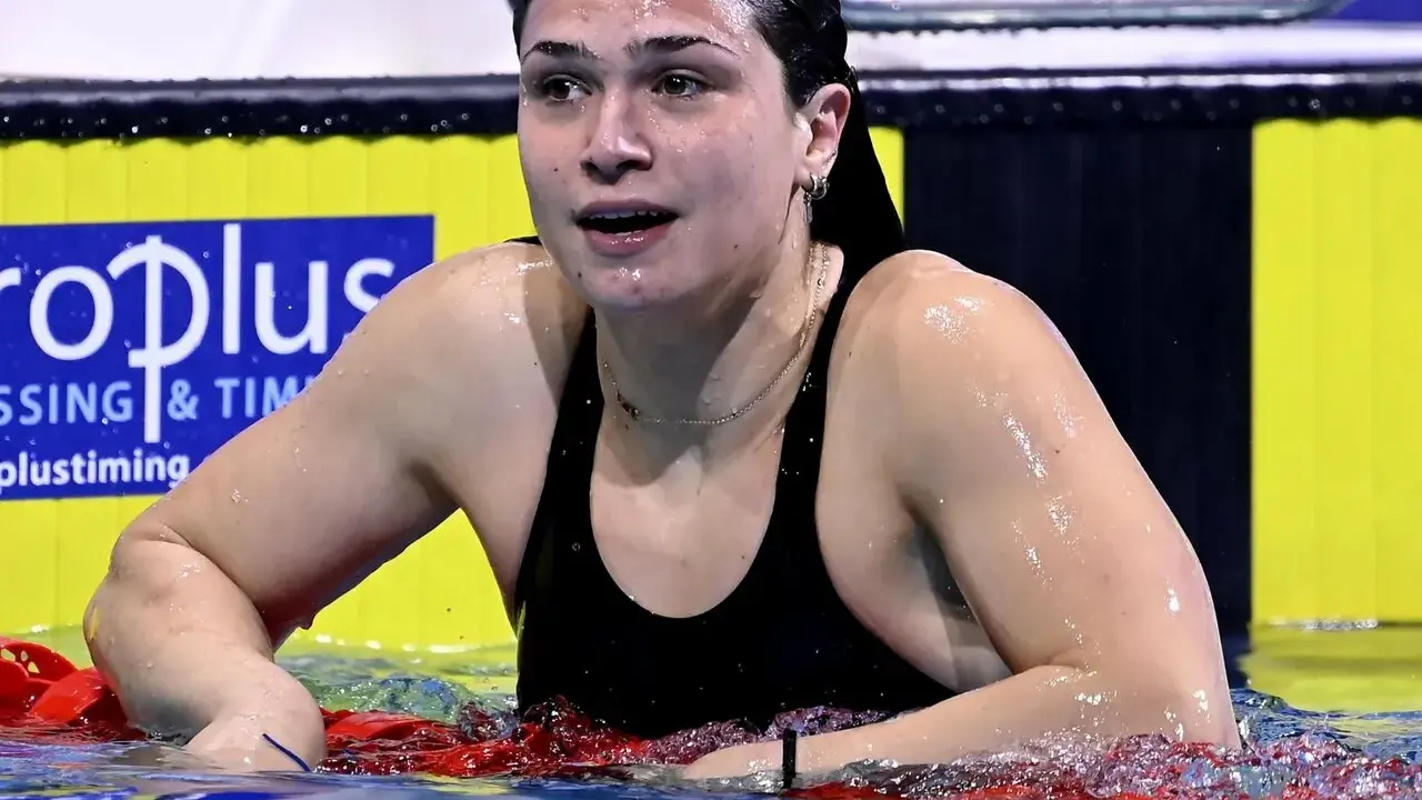 Benedetta Pilato, giovane campionessa di nuoto, emerge dall'acqua dopo una gara. La sua età non limita la sua forza.