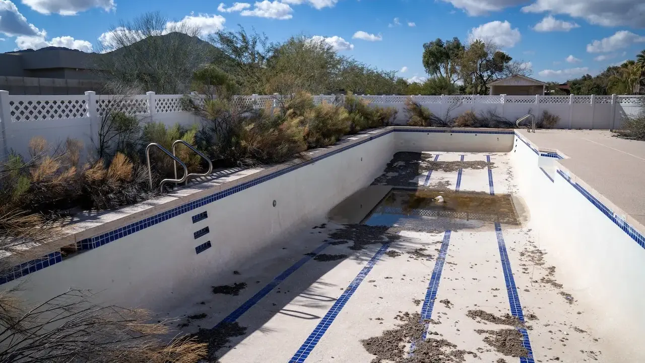 Piscina vuota e sporca, con detriti sul fondo. Immagina come svuotare la piscina con la pompa a sabbia per riportarla al suo antico splendore.