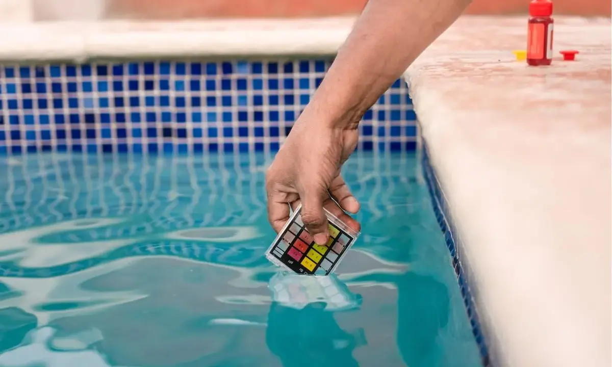 Mano immerge kit test pH nell'acqua della piscina, per assicurarsi che non sia acqua viscida.