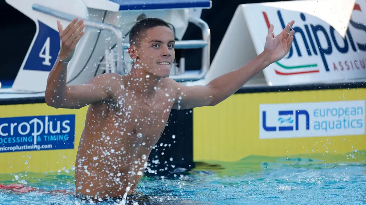 David Popovici esulta in piscina, circondato da schizzi d'acqua, con il numero 4 sulla corsia.