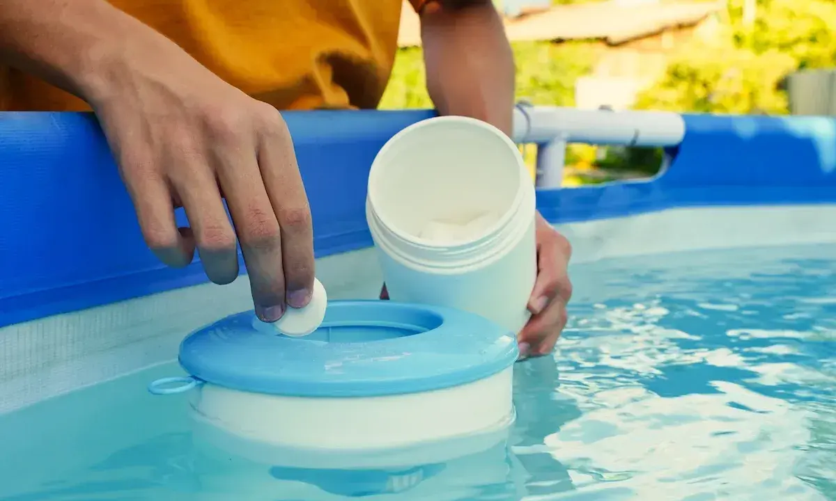 Mano inserisce una pastiglia nel galleggiante per la piscina. Un modo semplice per capire come pulire il filtro della piscina.