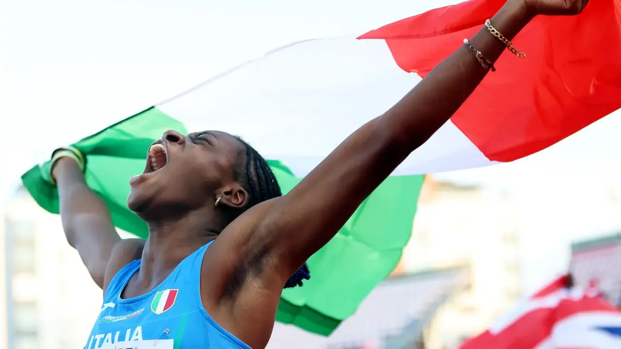 Atleta italiana esulta con la bandiera, un urlo di gioia per il record italiano 100 metri femminile.