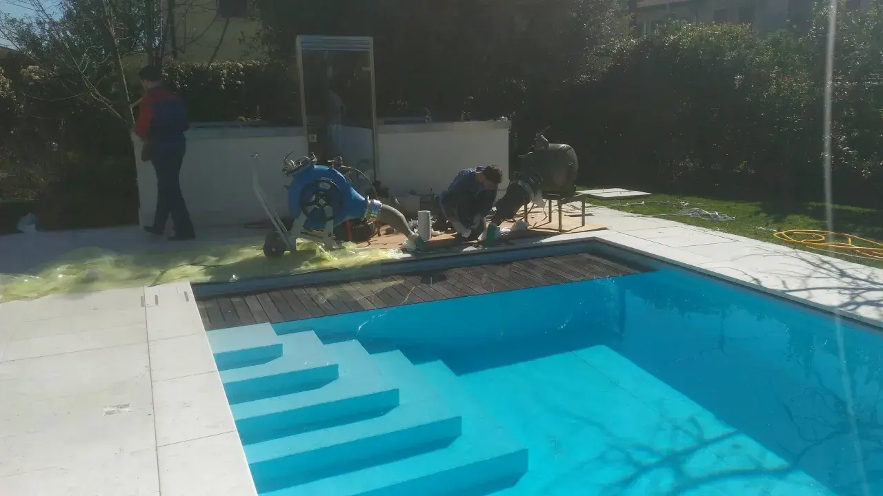 Tecnici al lavoro su una piscina Bestway che perde acqua da sotto, con attrezzature per la riparazione.