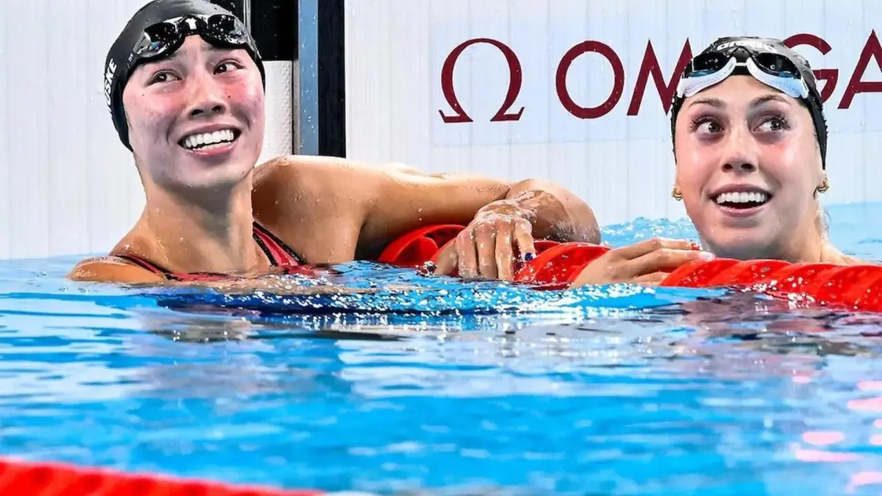 Due nuotatrici sorridono nell'acqua, una con il cappellino "Torri Huske".