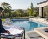 Uomo con occhiali studia progetto per capire come costruire una piscina interrata. Piscina moderna e giardino curato.