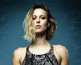 Francesca Pellegrini, nuotatrice con capelli bagnati e costume Jaked, posa con sguardo intenso su sfondo blu con riflessi d'acqua.