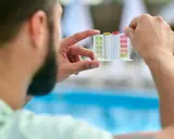 Uomo controlla il kit per acidificare l'acqua della piscina, analizzando i livelli di pH e cloro.
