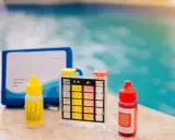 Kit per testare il cloro e il ph della piscina, con boccette di reagenti e strisce colorate.