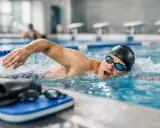 Atleta di nuoto master in azione, con bracciata potente e sguardo concentrato. La piscina è il suo regno.