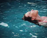 Donna galleggia serena, un passo verso come vincere la paura dell'acqua da adulti. L'acqua turchese la culla, simbolo di pace ritrovata.