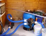 Sistema di filtrazione per piscina con filtro a sabbia, pompa e tubi blu. Il filtro a sabbia è il cuore del sistema per mantenere l'acqua pulita.