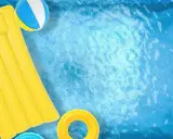Un materassino giallo, una palla e un salvagente galleggiano in una piscina azzurra. Ideale per scoprire come pulire piscina gonfiabile.