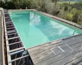 Struttura metallica a vista per piscina fuori terra, con pannelli in legno in fase di posa. Si nota un leggero cedimento della struttura.