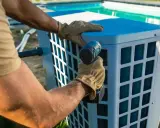 Installazione di un sistema per riscaldare acqua piscina fai da te. Un uomo con guanti avvita un componente.