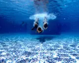 Subacquea, tre persone si tuffano in piscina. Chissà in quanto tempo un adulto impara a nuotare, ma loro sembrano già a loro agio.