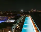 Una splendida piscina di sera, illuminata da luci soffuse, con la silhouette di Firenze sullo sfondo.