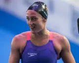 Mireia Belmonte, bagnata e sorridente, indossa un costume da nuoto viola e una cuffia nera.