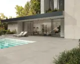 Moderna villa con piscina e ampia pavimentazione bordo piscina in gres. Due lettini prendisole invitano al relax.