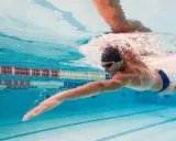 Nuotatore in azione, un'ottima dimostrazione che il nuoto fa dimagrire. L'acqua cristallina della piscina riflette la sua determinazione.