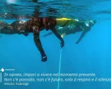 Due apneisti nuotano sott'acqua, uno vicino alla superficie. Imparare a trattenere il respiro, come rompere il fiato, porta a vivere il momento presente.
