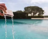 Mano che versa acqua da un contenitore per testare il cloro della piscina.