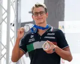 Davide Grossi, nuotatore italiano, mostra con orgoglio le sue medaglie d'argento e di bronzo, frutto di un'ottima prestazione.