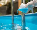 Versando antialghe piscina. Dopo quanto fare il bagno? La soluzione azzurra cade in acqua limpida.