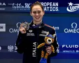 Anita Gastaldi sorride con una medaglia al collo e un peluche di ghepardo, celebrando una vittoria.
