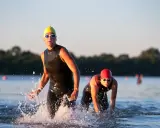 Atleti in muta escono dall'acqua, pronti per la corsa dopo il nuoto.