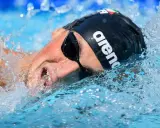 Nuotatore con cuffia Arena e occhialini, immerso nell'acqua con spruzzi. Potrebbe essere Pasquale Giordano in azione.