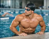 Atleta muscoloso in piscina, con cuffia e occhialini. Il nuoto fa crescere in altezza, scolpendo il corpo e migliorando la postura.