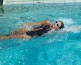 Donna nuota a stile libero in piscina, dimostrando che nuotare fa bene per mantenersi in forma e rilassarsi.