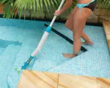 Donna usa un aspiratore per pulire il fondo della piscina, rimuovendo foglie e detriti per un'acqua cristallina.
