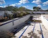Piscina vuota e sporca, con detriti sul fondo. Immagina come svuotare la piscina con la pompa a sabbia per riportarla al suo antico splendore.