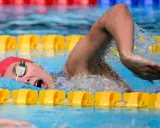 Nuotatrice con cuffia rossa e occhialini, in azione in piscina. Camille Muffat, un'atleta determinata.