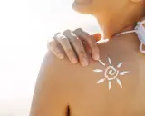 Sole sulla pelle, ma attenzione: il cloro toglie l'abbronzatura. Crema solare a forma di sole sulla spalla di una donna in spiaggia.