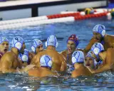 Giocatori di pallanuoto in acqua, con cuffie numerate, in un momento di intensa competizione. I loro ruoli pallanuoto sono evidenti dalla loro posizione e dall'azione.