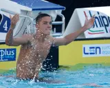 David Popovici esulta in piscina, circondato da schizzi d'acqua, con il numero 4 sulla corsia.