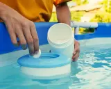 Mano inserisce una pastiglia nel galleggiante per la piscina. Un modo semplice per capire come pulire il filtro della piscina.